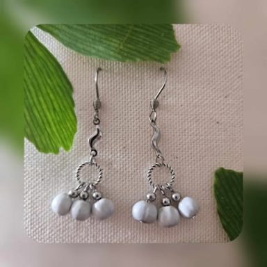 Boucles d'oreilles en argent avec perles blanches pendantes et élément en spirale.